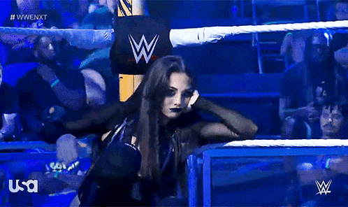 A Woman In A Wrestling Ring With A W Logo In The Background GIF