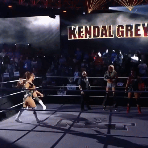a woman in a wrestling ring with kendal grey written on a large screen behind her