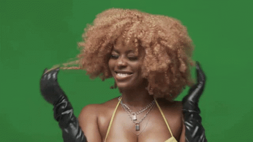 A Woman In A Yellow Bikini And Black Gloves Is Smiling On A Green Background . GIF