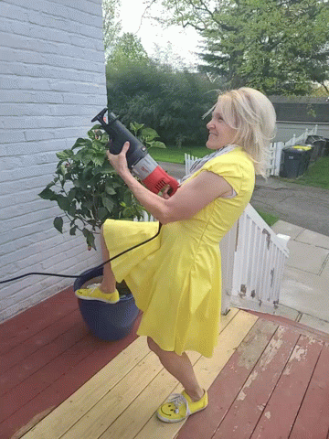 A Woman In A Yellow Dress Holds A Red Saw GIF