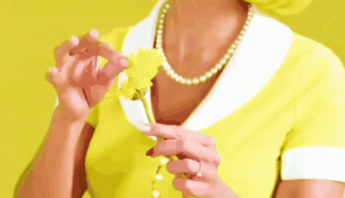A Woman In A Yellow Dress Is Holding A Yellow Flower . GIF