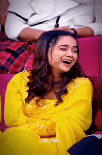 A Woman In A Yellow Dress Is Laughing With Her Eyes Closed GIF