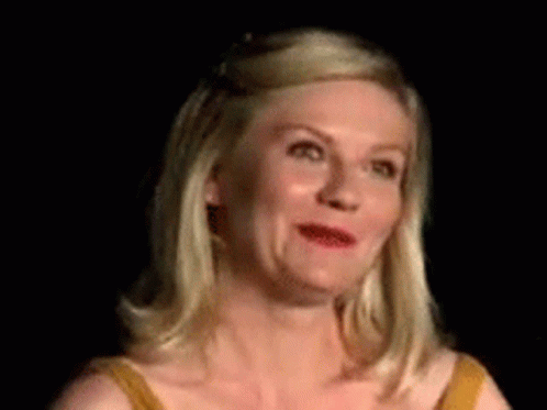 A Woman In A Yellow Dress Is Making A Funny Face In A Dark Room . GIF