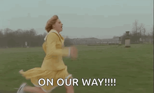 A Woman In A Yellow Dress Is Running In A Field And Saying `` On Our Way '' . GIF