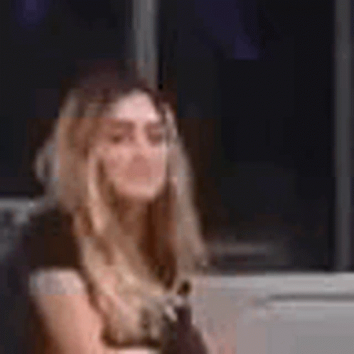 A Woman In A Yellow Dress Is Sitting In Front Of A Window And Talking On A Cell Phone . GIF