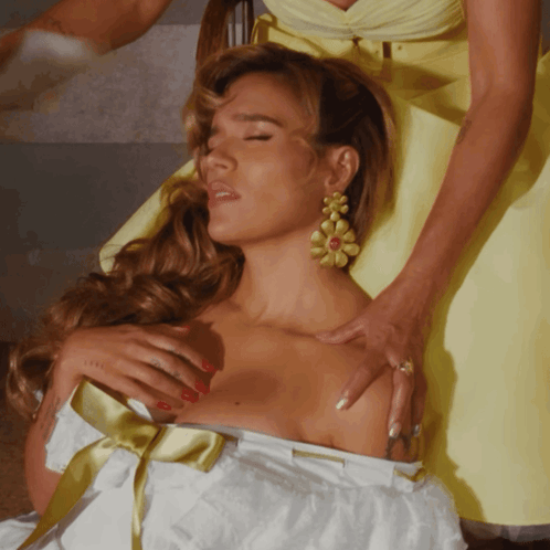 A Woman In A Yellow Dress Is Touching Another Woman 'S Breast GIF