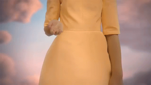 a woman in a yellow dress reaches out her hand towards a cloudy sky