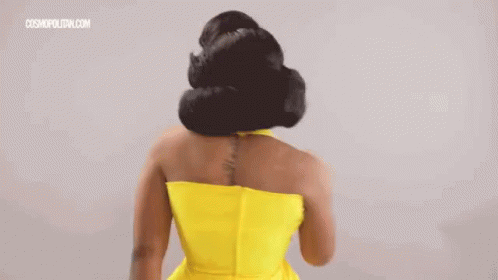 A Woman In A Yellow Dress With A Tattoo On Her Back Is Standing With Her Back To The Camera . GIF