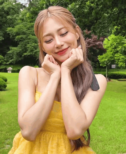 A Woman In A Yellow Dress With Her Hands On Her Face GIF