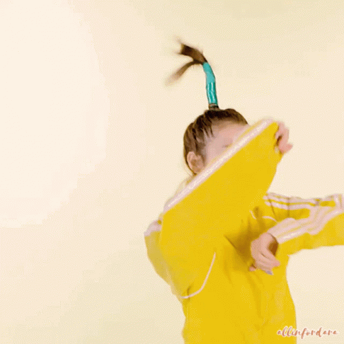 A Woman In A Yellow Jacket Has A Blue Ponytail In Her Hair GIF