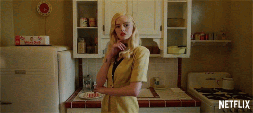 A Woman In A Yellow Jacket Stands In A Kitchen With A Netflix Logo On The Bottom GIF