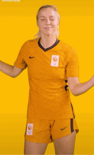 A Woman In A Yellow Nike Shirt And Shorts Is Dancing On A Yellow Background GIF