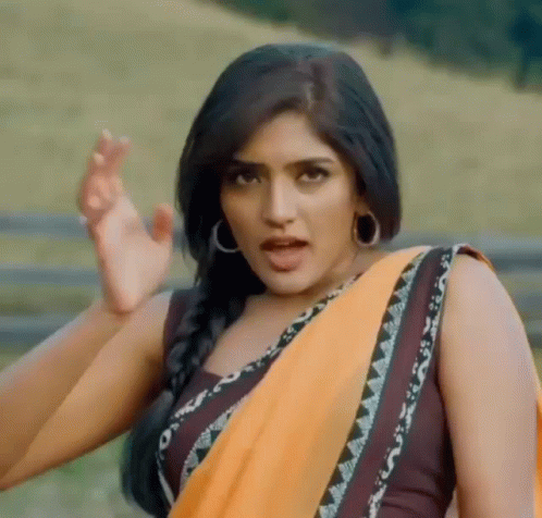 A Woman In A Yellow Saree Is Making A Funny Face While Standing In A Field . GIF