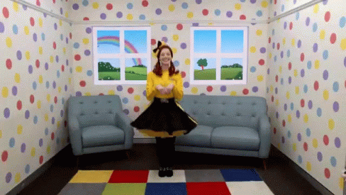 A Woman In A Yellow Shirt And Black Skirt Is Dancing In A Room With Polka Dot Wallpaper GIF
