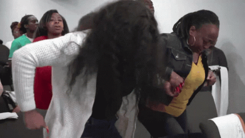 A Woman In A Yellow Shirt Is Being Held By Another Woman In A White Sweater GIF