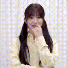 A Woman In A Yellow Shirt Is Covering Her Mouth With Her Hand And Smiling . GIF