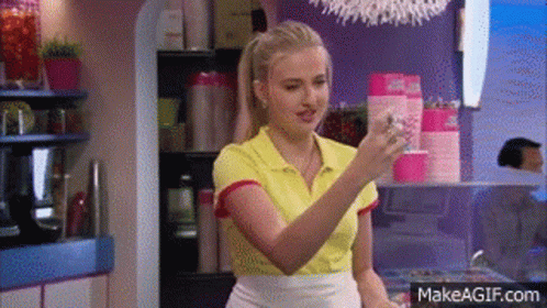 A Woman In A Yellow Shirt Is Holding A Glass Of Water In A Kitchen . GIF