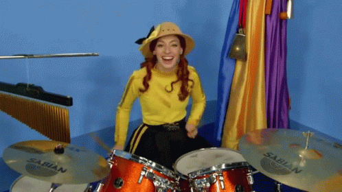 A Woman In A Yellow Shirt Is Playing A Sabian Drum Set GIF