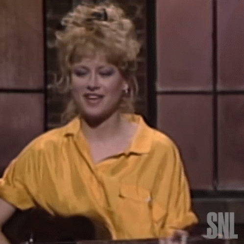 A Woman In A Yellow Shirt Is Sitting At A Table With A Glass Of Wine . GIF