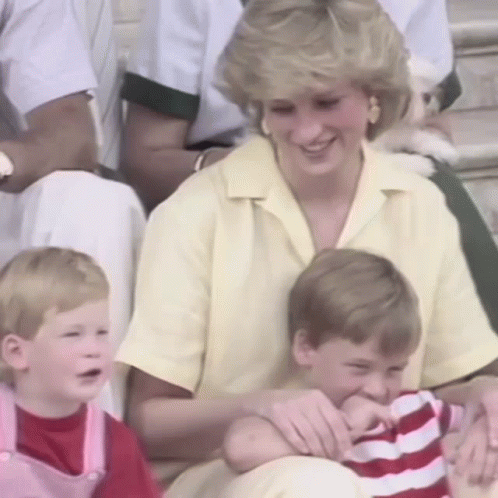 A Woman In A Yellow Shirt Is Sitting With Two Children And A Dog . GIF