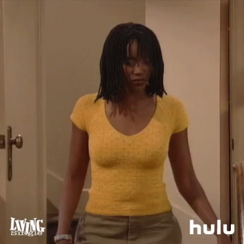 A Woman In A Yellow Shirt Is Standing In A Doorway With A Hulu Logo In The Corner GIF