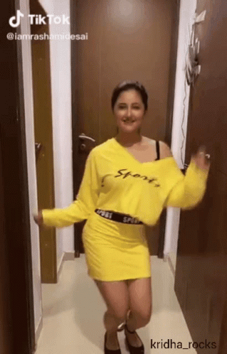 A Woman In A Yellow Sweater And Skirt Is Dancing GIF