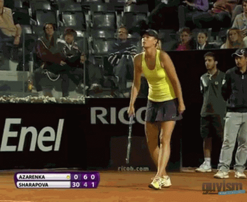 A Woman In A Yellow Tank Top Is Holding A Tennis Racquet In Front Of A Sign That Says Enel GIF