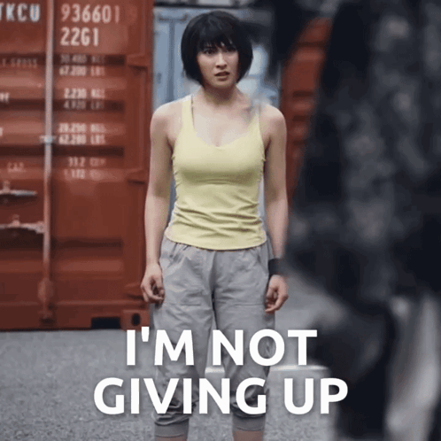 A Woman In A Yellow Tank Top Is Standing In Front Of A Red Container That Says Tkcu 2261 GIF
