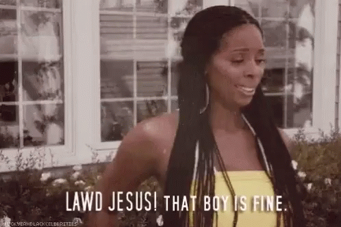 A Woman In A Yellow Tank Top Is Standing In Front Of A Window And Saying Lawd Jesus ! That Boy Is Fine . GIF