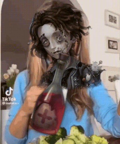 A Woman In A Zombie Costume Is Drinking From A Bottle While Eating Vegetables . GIF