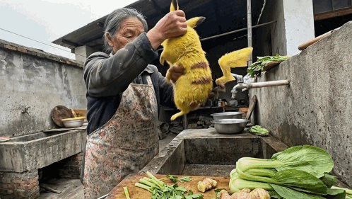 A Woman In An Apron Is Holding A Yellow Animal Over A Cutting Board GIF
