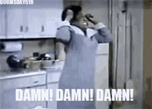 A Woman In An Apron Is Standing In A Kitchen Talking On A Cell Phone And Making A Funny Face . GIF