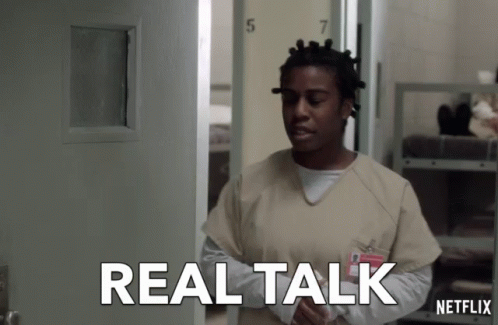 A Woman In An Orange Scrub Stands In Front Of A Door That Says Real Talk Netflix GIF
