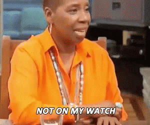 A Woman In An Orange Shirt Is Sitting At A Table With A Glass Of Water And Says `` Not On My Watch '' . GIF