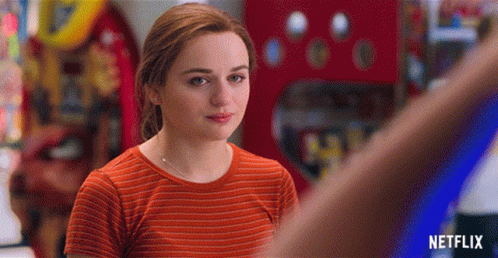 A Woman In An Orange Striped Shirt Is Standing In Front Of A Netflix Logo GIF