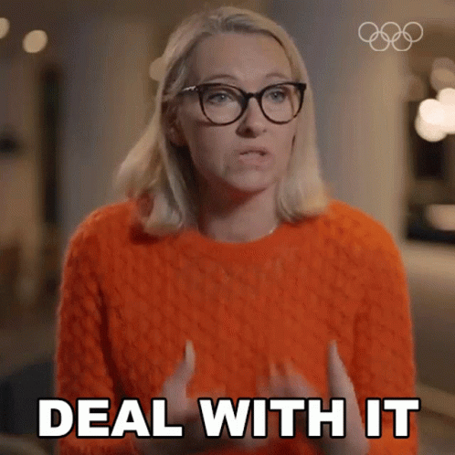 A Woman In An Orange Sweater And Glasses Says Deal With It GIF