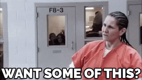 A Woman In An Orange Uniform Is Standing In Front Of A Door And Asking , `` Want Some Of This ? '' GIF