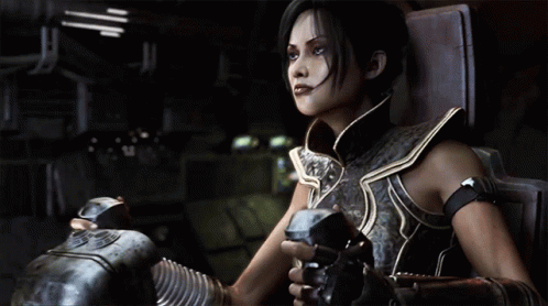 A Woman In Armor Is Sitting In A Chair Holding A Gun GIF