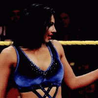 A Woman In Blue Shorts Is Standing In A Wrestling Ring With Another Woman GIF