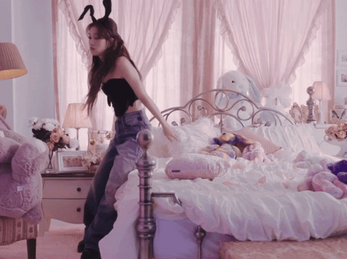 A Woman In Bunny Ears Stands On A Bed GIF