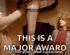 A Woman In Fishnet Stockings Is Standing Next To A Man In A Brown Jacket . GIF