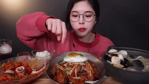 a woman in glasses is eating a plate of food with a fried egg on top