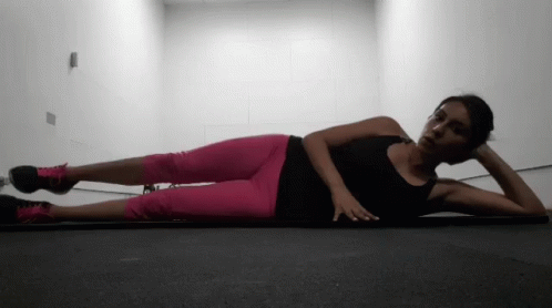 A Woman In Pink Pants Is Laying On The Floor GIF
