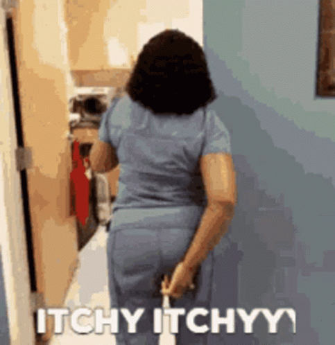 A Woman In Scrubs Is Walking Down A Hallway With The Words Itchy Itchyy Written On The Wall Behind Her GIF