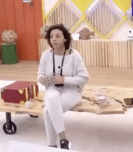 a woman in white pants is sitting on a wooden table .