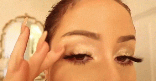 A Woman Is Applying Eye Shadow To Her Eye . GIF