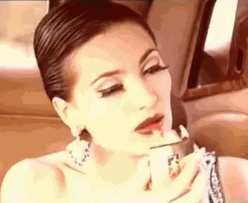 A Woman Is Applying Lipstick In A Car While Sitting In The Back Seat . GIF