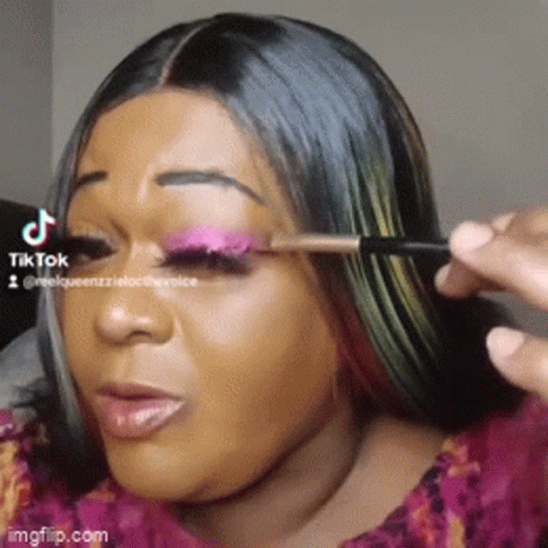 A Woman Is Applying Makeup To Her Eye With A Brush GIF