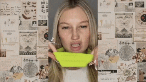 A Woman Is Applying Makeup To Her Face In Front Of A Wall Of Papers . GIF