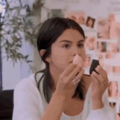A Woman Is Applying Makeup With A Sponge . GIF